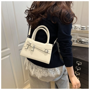 Detail of a creamy white crossbody bag with bow decoration shown on a model