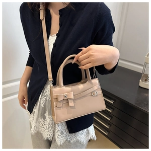 Detail view of beige bow-knot handbag with elegant crossbody strap and hardware