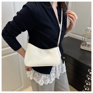 Close-up of white crescent shoulder bag with slim strap and gold metal buckle