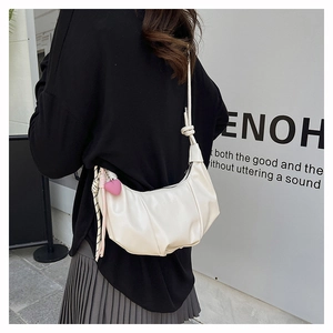 Chic beige ruched crescent bag with shoulder strap and pink heart charm in street view