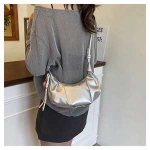 Detail of silver metallic dumpling bag showing pleated texture and glossy finish on model