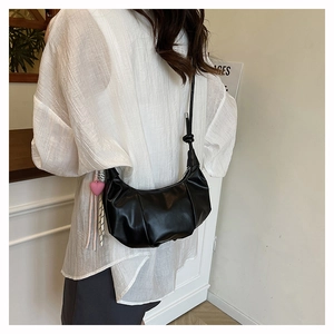 Detail of black pleated crescent bag with knot strap and pink heart charm
