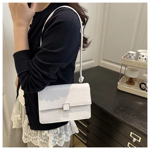 Detailed side view of a white crocodile texture shoulder bag on a female model