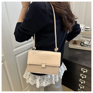 Model wearing a beige crocodile texture crossbody bag with unique knot shoulder strap