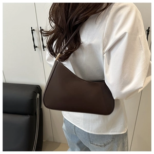 Detail of a dark brown crescent shoulder bag with adjustable strap worn on the shoulder