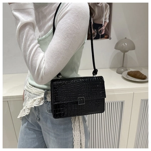 Detail of a vintage black crocodile pattern shoulder bag with a silver square metal buckle