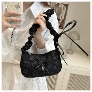Vista detallada del bolso dumpling de jacquard negro con lazo y dije de corazón