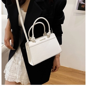 Detail of white crocodile embossed leather tote showing round handles and FASHION BAG text