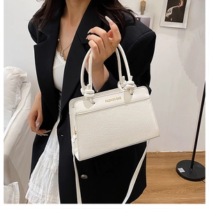 White crocodile pattern handbag with knot handle worn by a model in a minimal setting