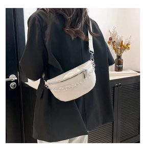 Model wearing a white crescent-shaped crossbody bag with silver chain in casual setting