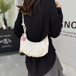 Minimalist white crescent dumpling bag with woven strap and heart charm on female model