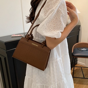 Dark brown crocodile-embossed tote bag with gold lettering and knotted double handles