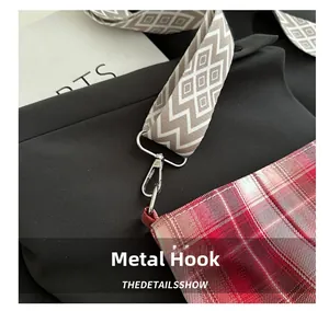 Detailed view of red checkered canvas tote with a wide shoulder strap and silver hook