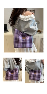 Detailed view of purple plaid canvas tote bag featuring brown leather logo and woven strap