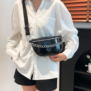 Chic black saddle bag with silver chain and wide strap on model in modern interior