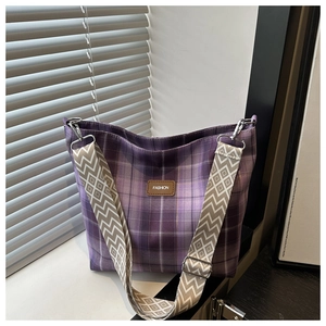 Detail of purple plaid canvas tote bag with woven strap and fashion leather patch