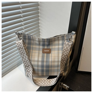Detail of plaid canvas tote with leather fashion tag and geometric jacquard strap