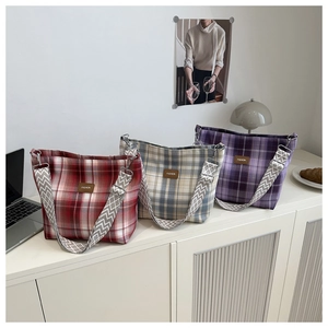 Close-up of three checkered canvas tote bags in red, grey, and purple with fashion leather labels