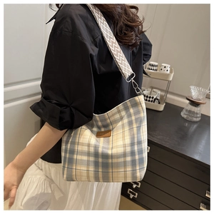 Detail of checkered canvas crossbody bag with wide geometric pattern strap and leather tag