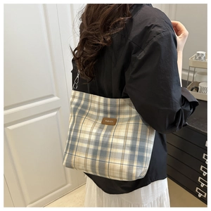 Detail of checkered shoulder bag featuring woven fabric texture and metal chain strap