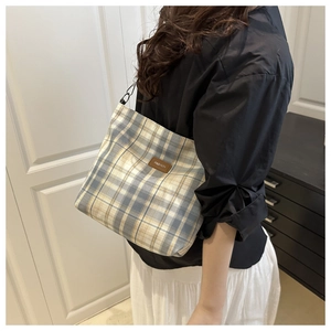 Detail of blue and yellow plaid shoulder bag featuring a leather FASHION label patch