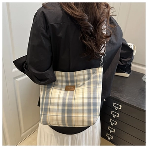 Close-up of yellow and blue plaid tote bag with FASHION leather tag and woven strap