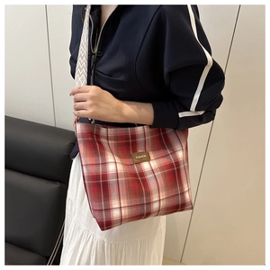 Detail of red plaid tote bag with FASHION leather tag and geometric woven shoulder strap