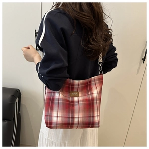 Detail view of a red plaid hobo shoulder bag featuring a leather fashion logo tag