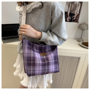 Detail of purple plaid tote bag with ethnic style wide woven shoulder strap in lifestyle setting