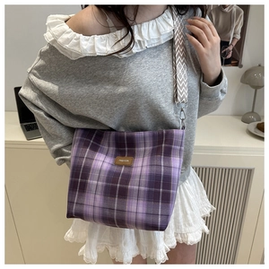 Detail of purple plaid canvas tote bag with wide geometric strap and fashion leather patch
