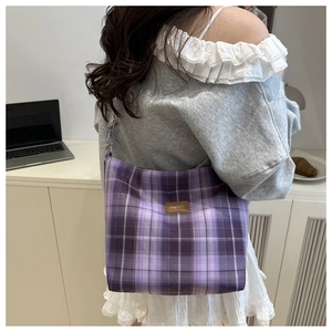 Detail of purple plaid tote bag with brown leather fashion patch on casual shoulder strap