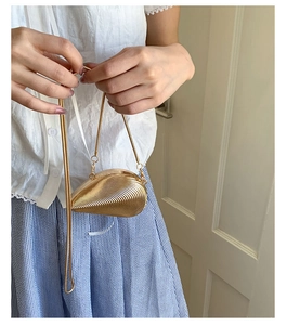 Macro detail of golden shell-shaped evening bag featuring unique wavy ripple texture