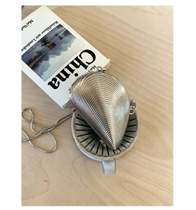 Detailed view of silver shell-shaped evening clutch with elegant snake chain accessory