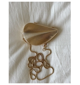 Close-up of gold shell clutch bag with pleated texture and metallic snake chain strap