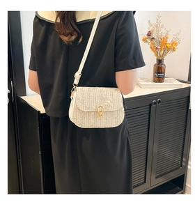 Detail of embroidered floral straw saddle bag with gold buckle on a navy dress