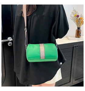 Green cylindrical crossbody bag featuring vintage wide jacquard strap on a model