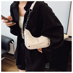 Detail of cream white underarm bag featuring silver chain strap and side stud accents
