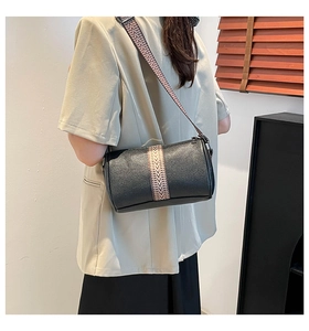 Close-up of black lychee grain pillow bag featuring geometric woven wide shoulder strap