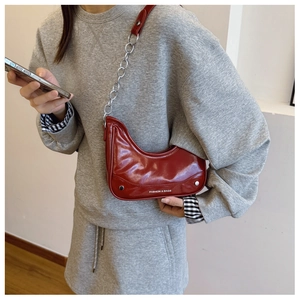 Detail shot of glossy red patent leather hobo bag with silver chain and brand text