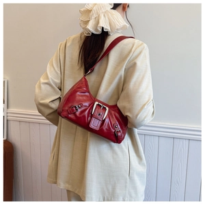 Detail of dark red vintage underarm bag with metal buckle worn with a beige suit