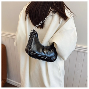 Close-up of black glossy shoulder bag featuring pleated PU leather and silver chain