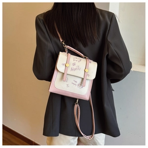 Detail der pink-weißen Umhängetasche mit Illustration auf einem dunklen Blazer