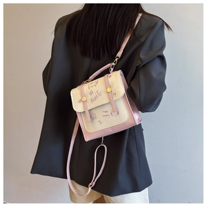 Detail einer pink-weißen Umhängetasche mit Cartoon-Prints und goldenem Schnallenverschluss