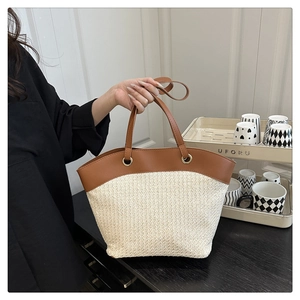 Detail of woven tote bag with cream texture, brown leather trim, and sturdy handles