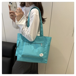 Détail du sac cabas en nylon bleu lac avec poche zippée fonctionnelle et étiquette ronde