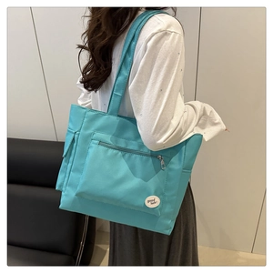 Detail of tiffany blue canvas tote bag featuring front zipper pocket and good luck patch