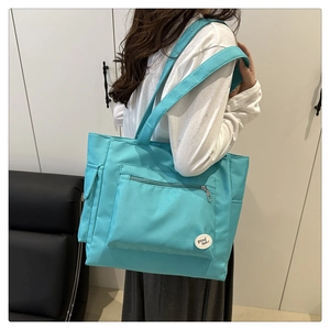 Détail du cabas en nylon sarcelle avec poche zippée et écusson décoratif Good Luck