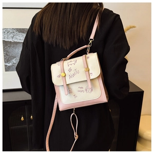 Detail einer rosa-cremefarbenen Umhängetasche mit künstlerischen Cartoons und goldenen Beschlägen