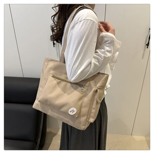 Vue détaillée du grand sac cabas beige en toile avec poches et écusson de bonne chance