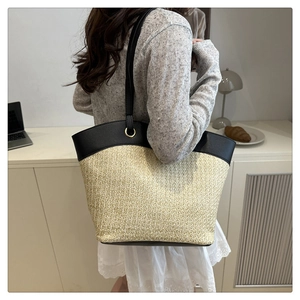 Detail of minimalist woven tote bag with premium black leather trim and shoulder strap